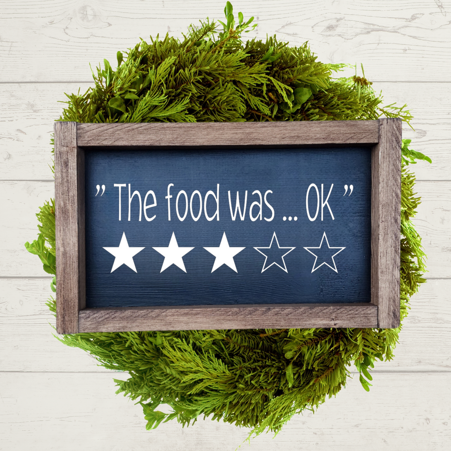 5x9 inch wooden kitchen sign that says the food was ok with a 3 star rating painted in black and white with a brown farmhouse frame.