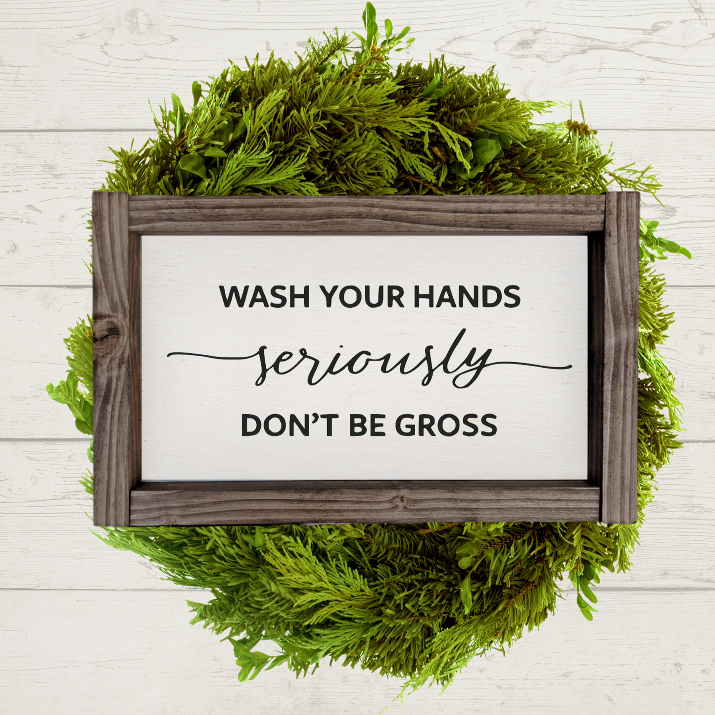 Black text that says wash your hands, seriously, don't be gross with a white background and brown stained frame in a 5x9 size.